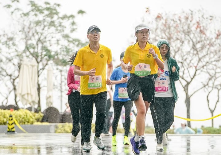 A man and a woman run in the rain wearing yellow Intertek t-shirts.