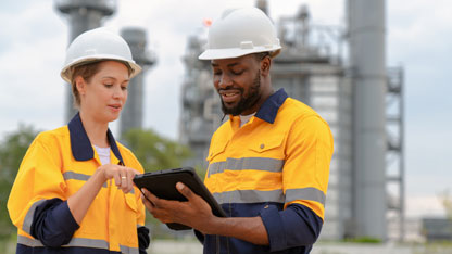 Two electrical plant engineers discuss power usage using a tablet