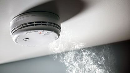 Smoke detector and interlinked fire alarm in action background